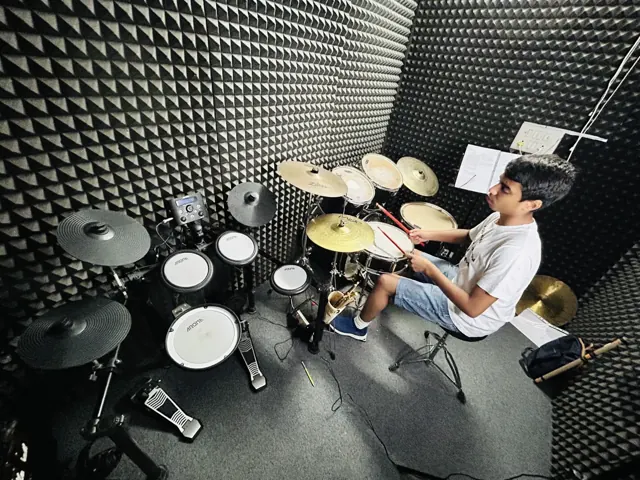 A learner practising on a drum kit at DSM