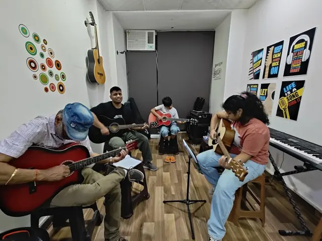 Children and adults practising acoustic guitar together at DSM Dwarka Sector 22