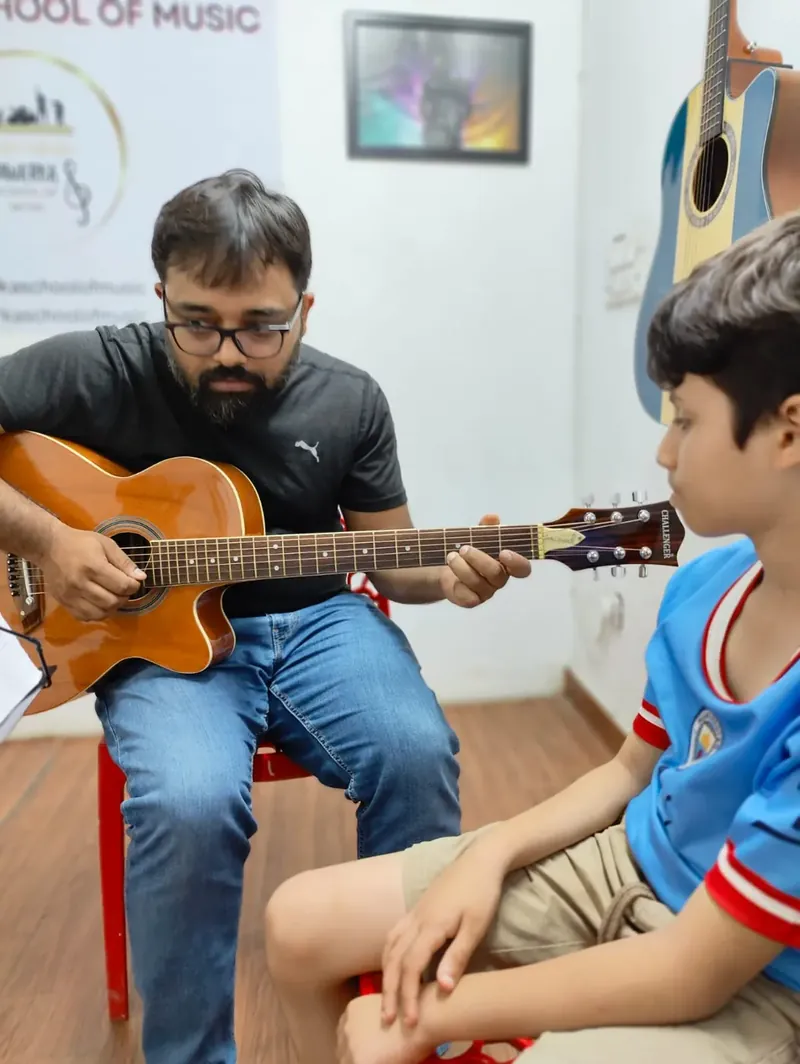 A teacher guiding a guitar learner during a DSM lesson