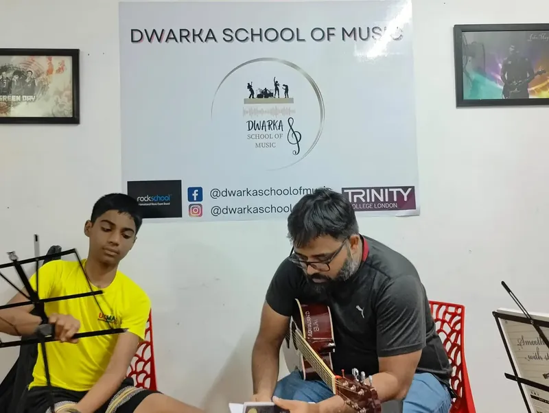 Two learners practising guitar together at Dwarka School of Music